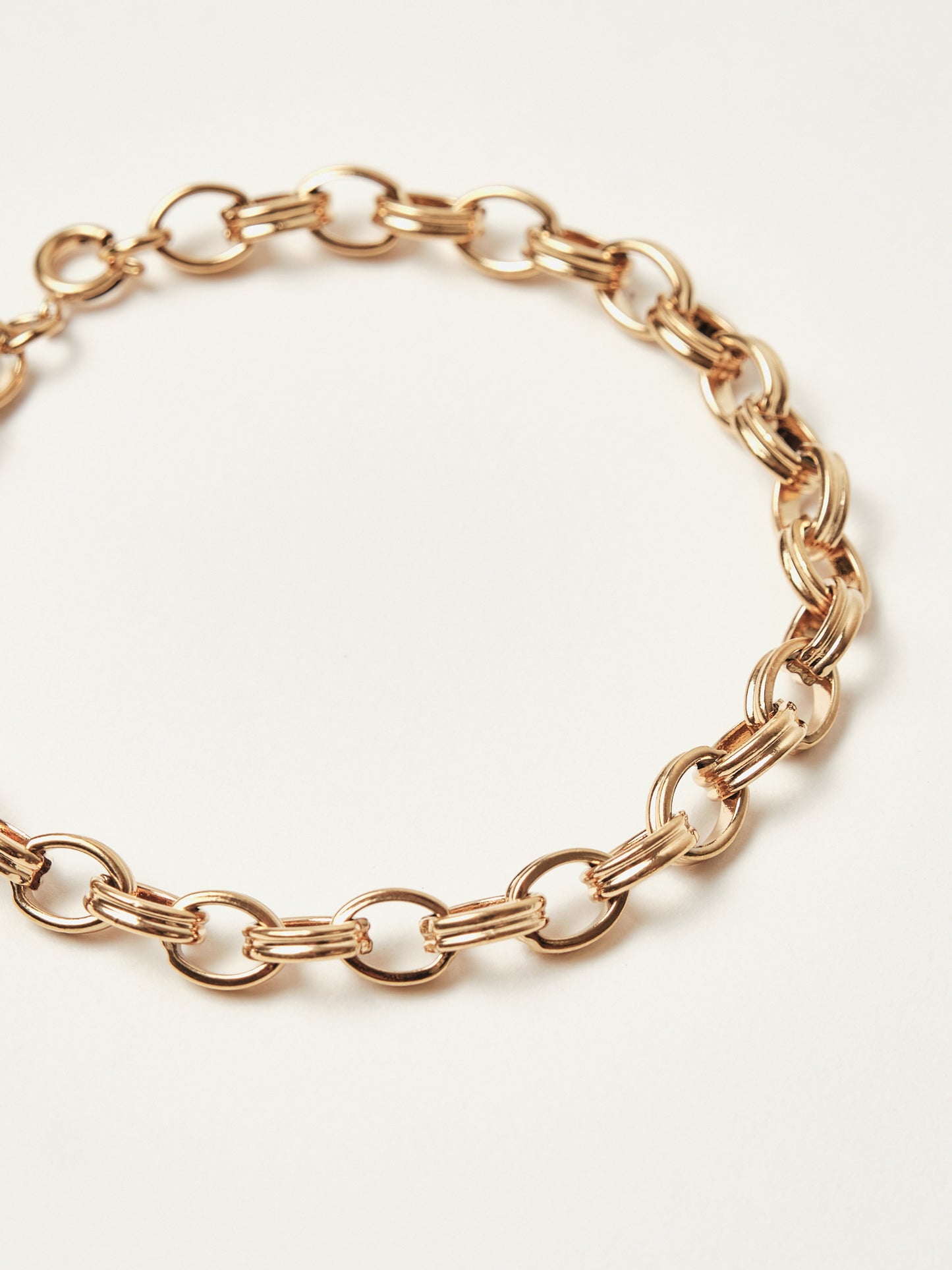 Rose gold chain bracelet on a light beige background