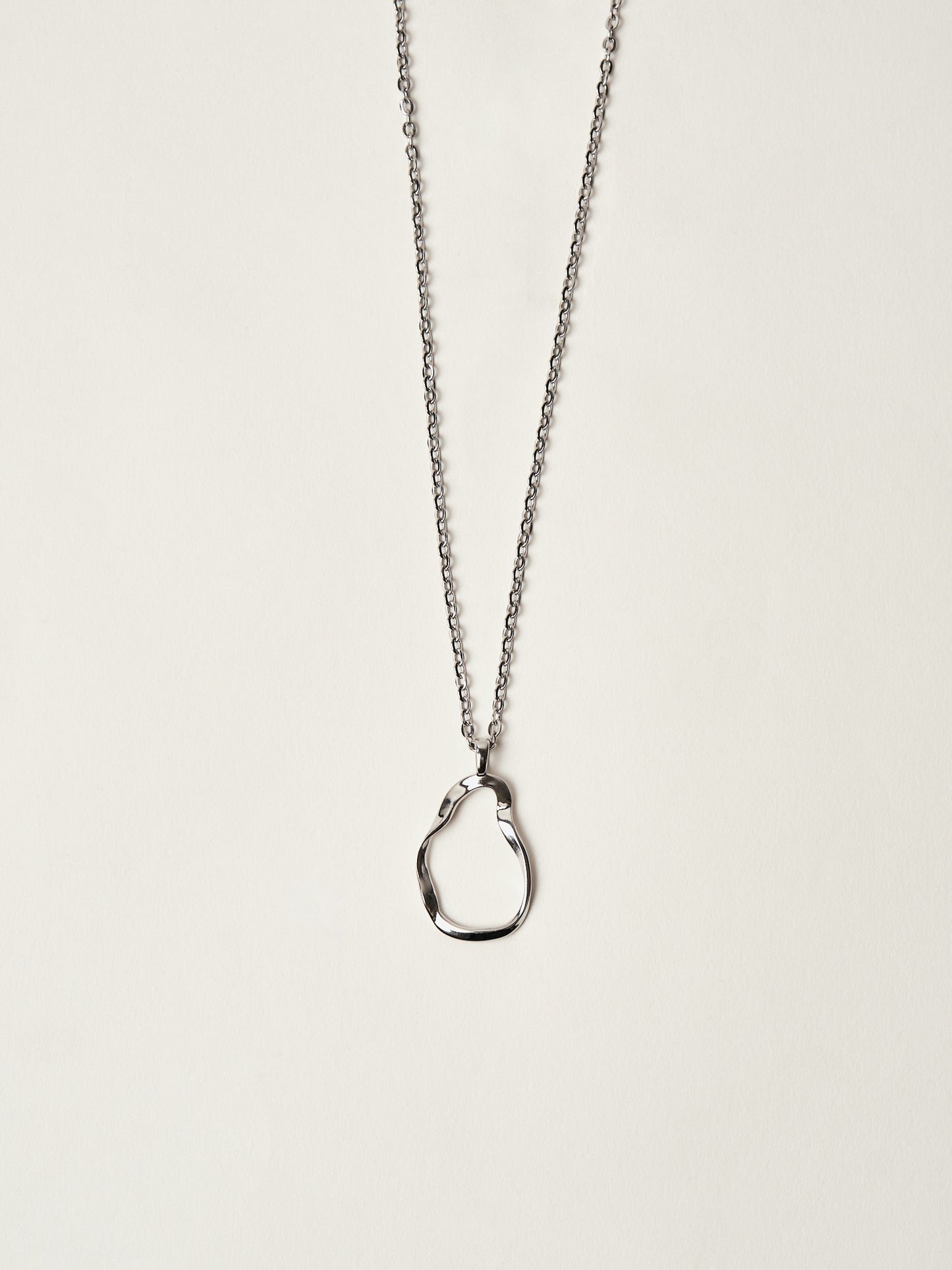 Silver necklace with a unique pendant on a light beige background