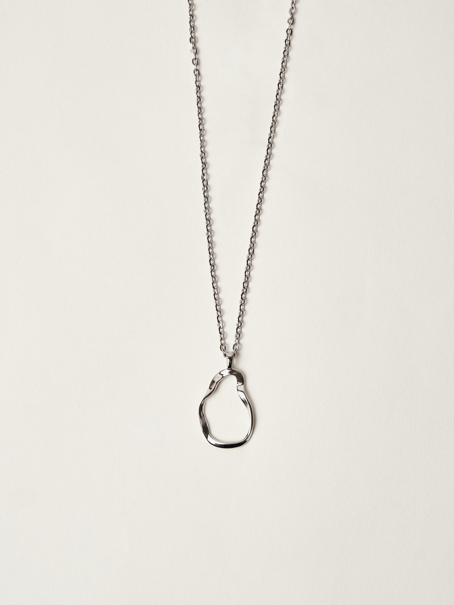 Silver necklace with a unique pendant on a light beige background