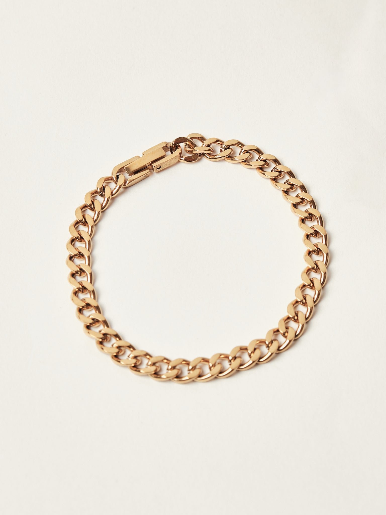 Gold chain bracelet on a light beige background