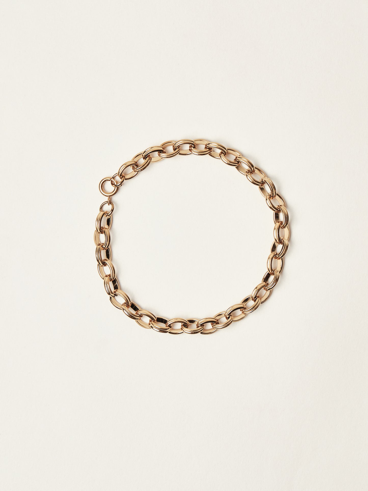 Gold chain bracelet on a beige background