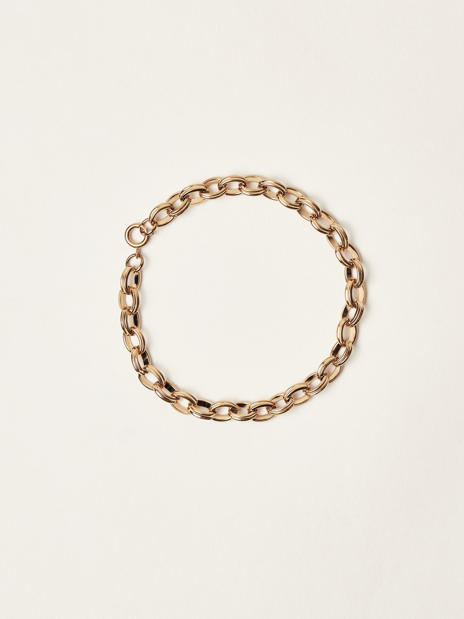 Gold chain bracelet on a beige background