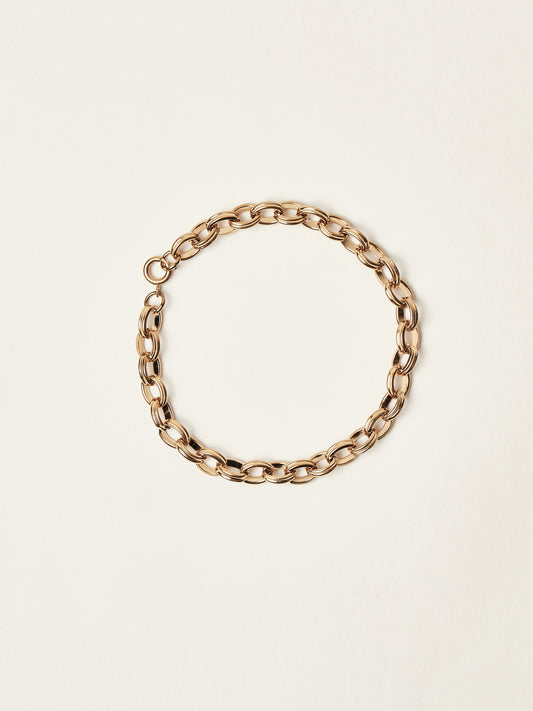 Gold chain bracelet on a beige background