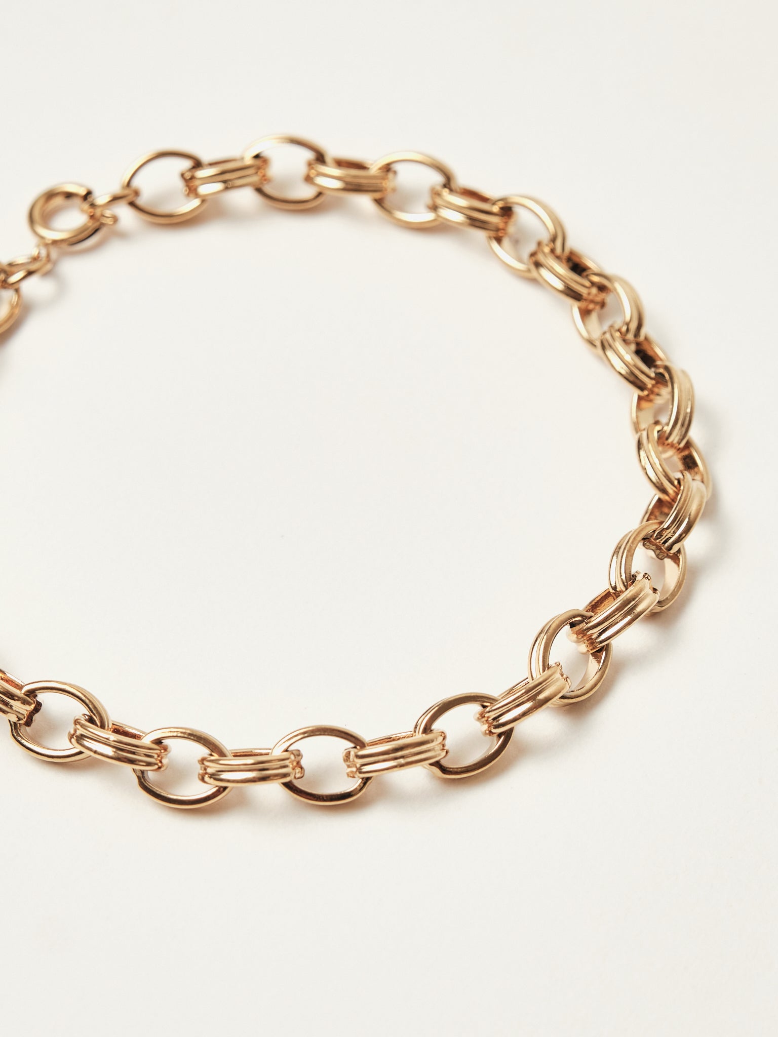 Rose gold chain bracelet on a light beige background