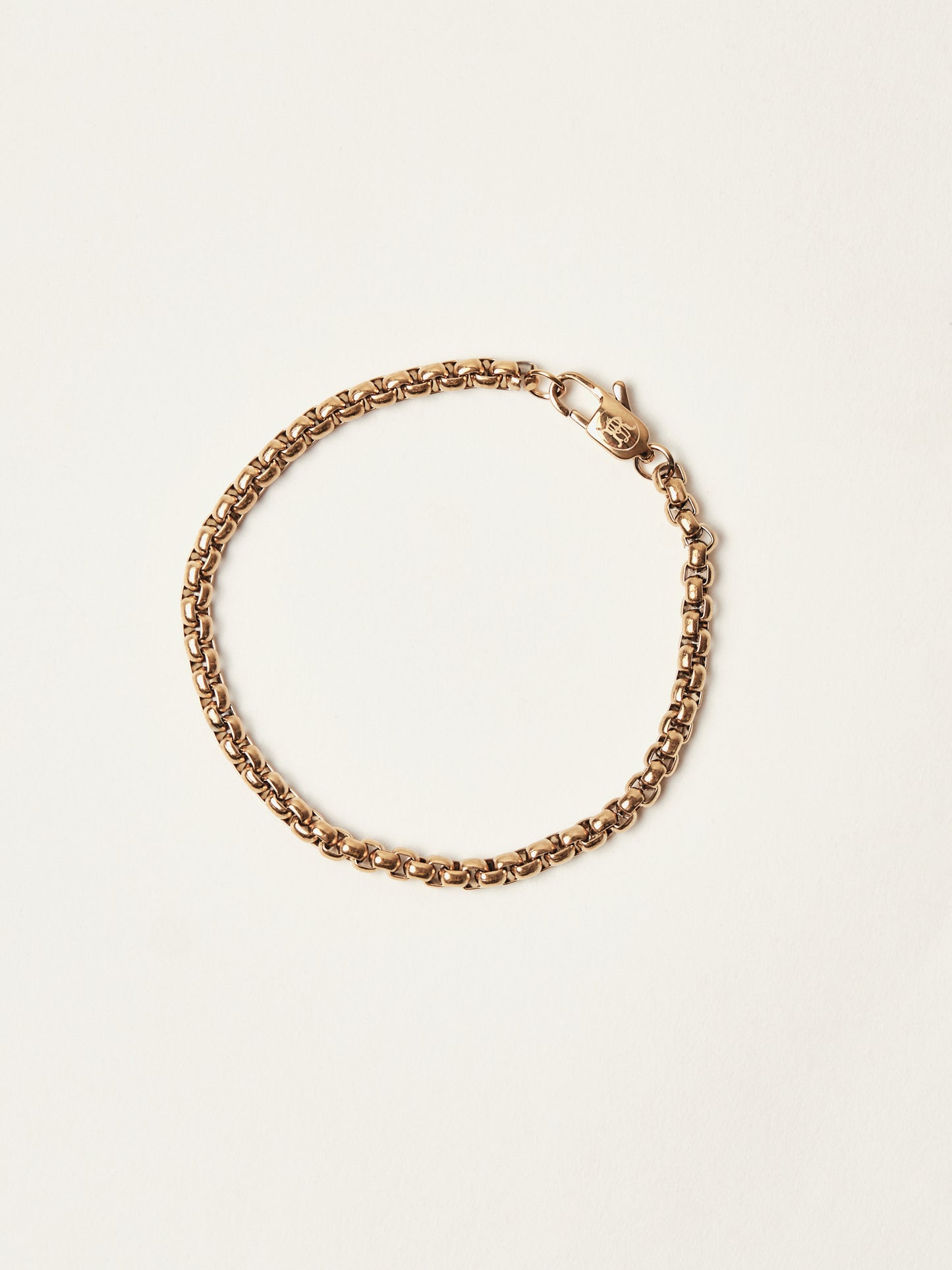 Gold chain bracelet on a light beige background