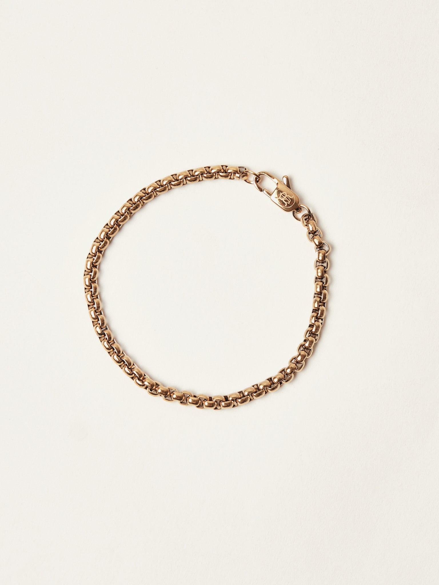 Gold chain bracelet on a light beige background