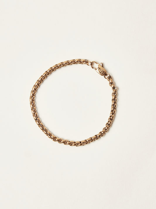 Gold chain bracelet on a light beige background