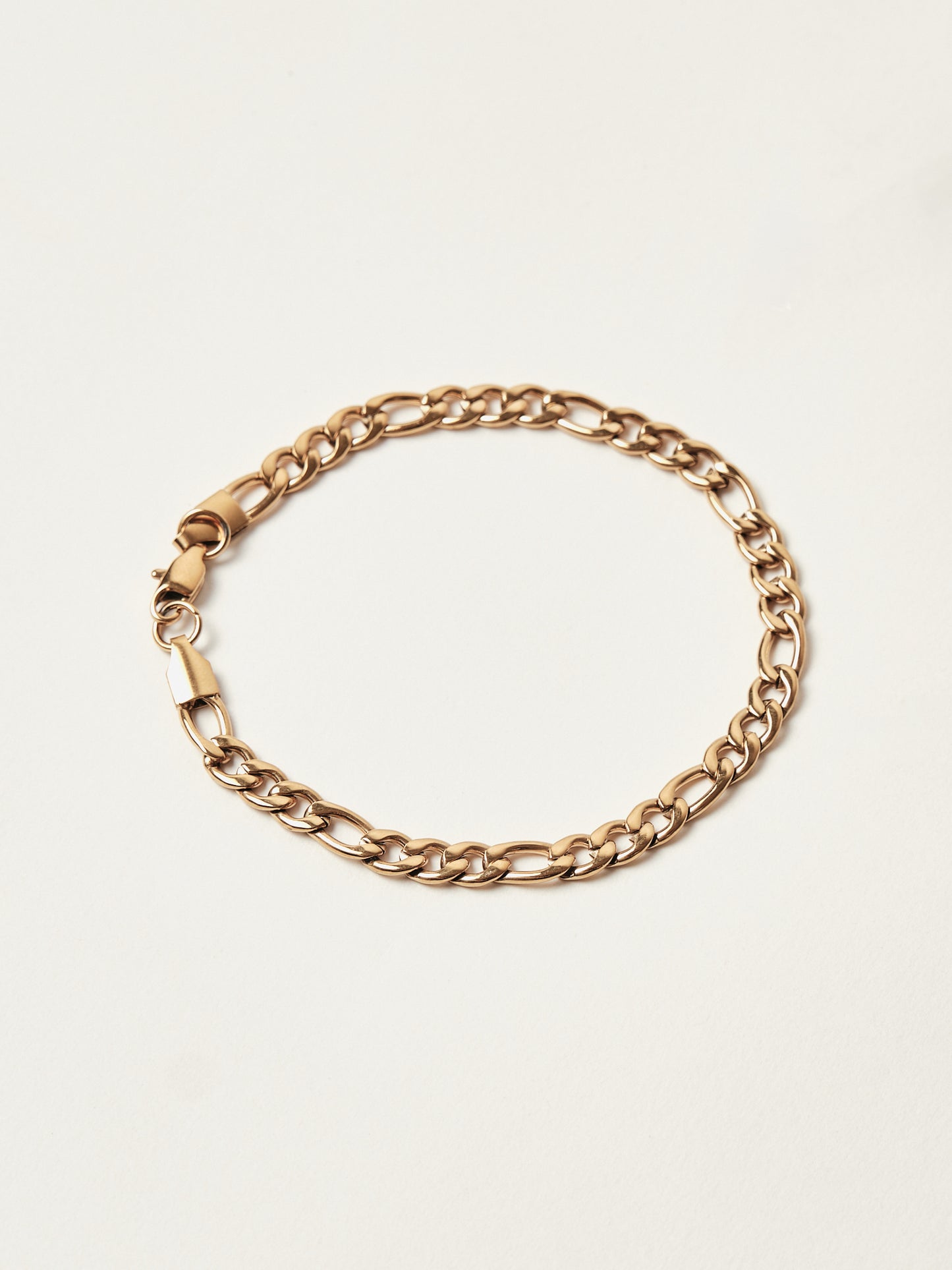 Gold chain bracelet on a light beige background