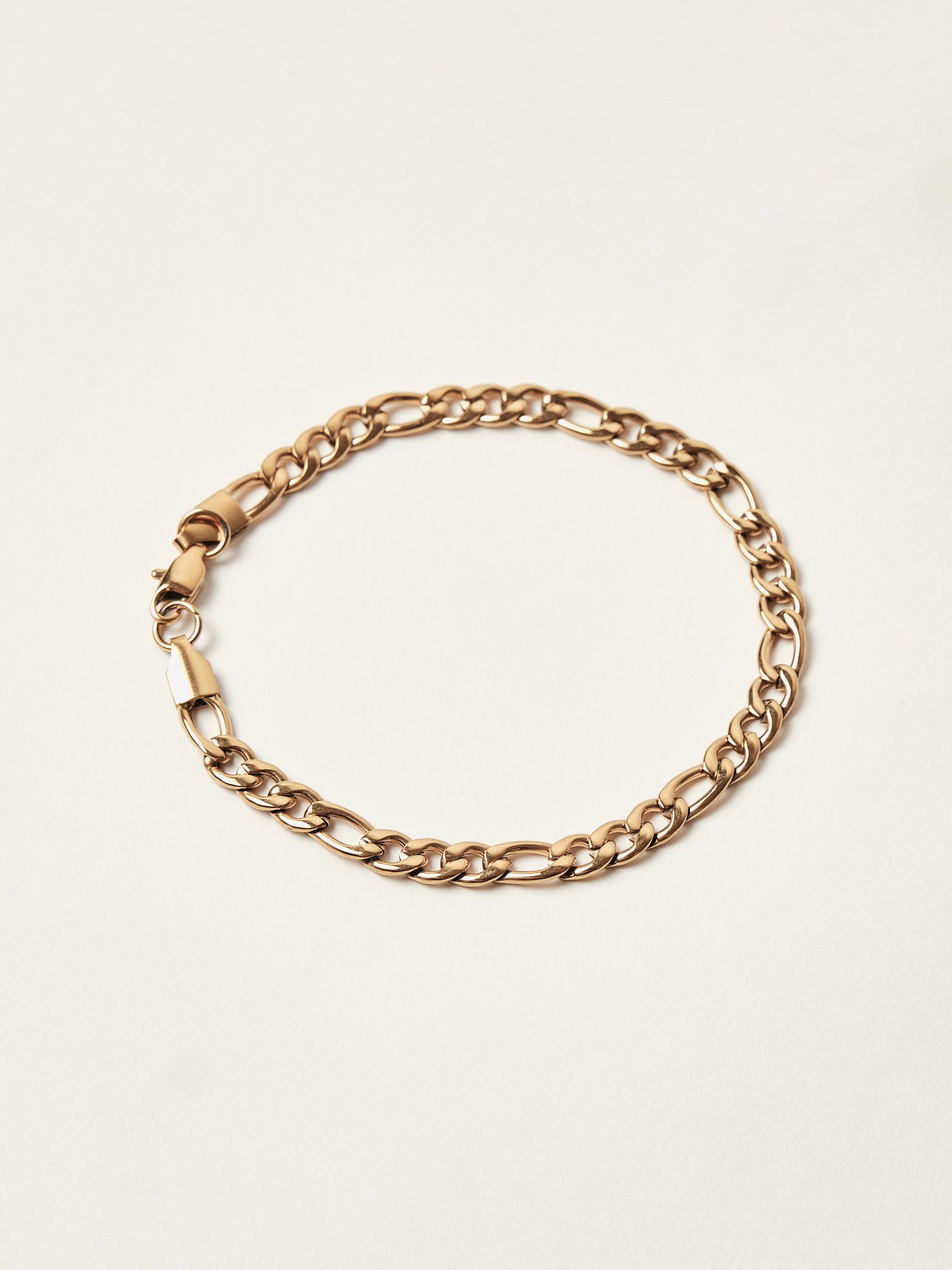 Gold chain bracelet on a light beige background