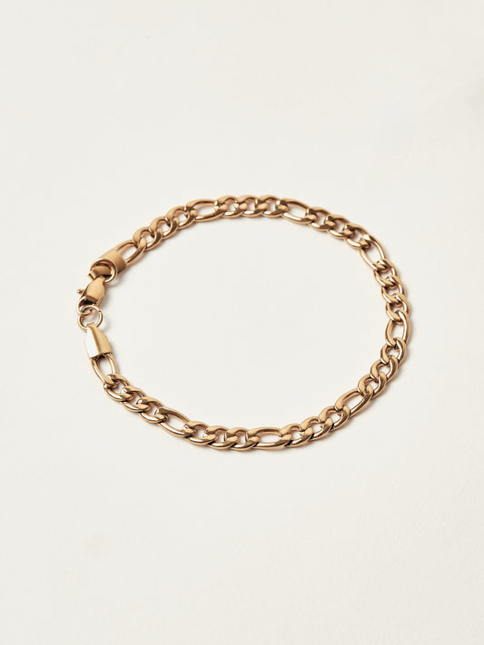 Gold chain bracelet on a light beige background