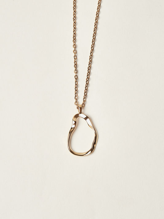 Gold necklace with a unique pendant on a beige background