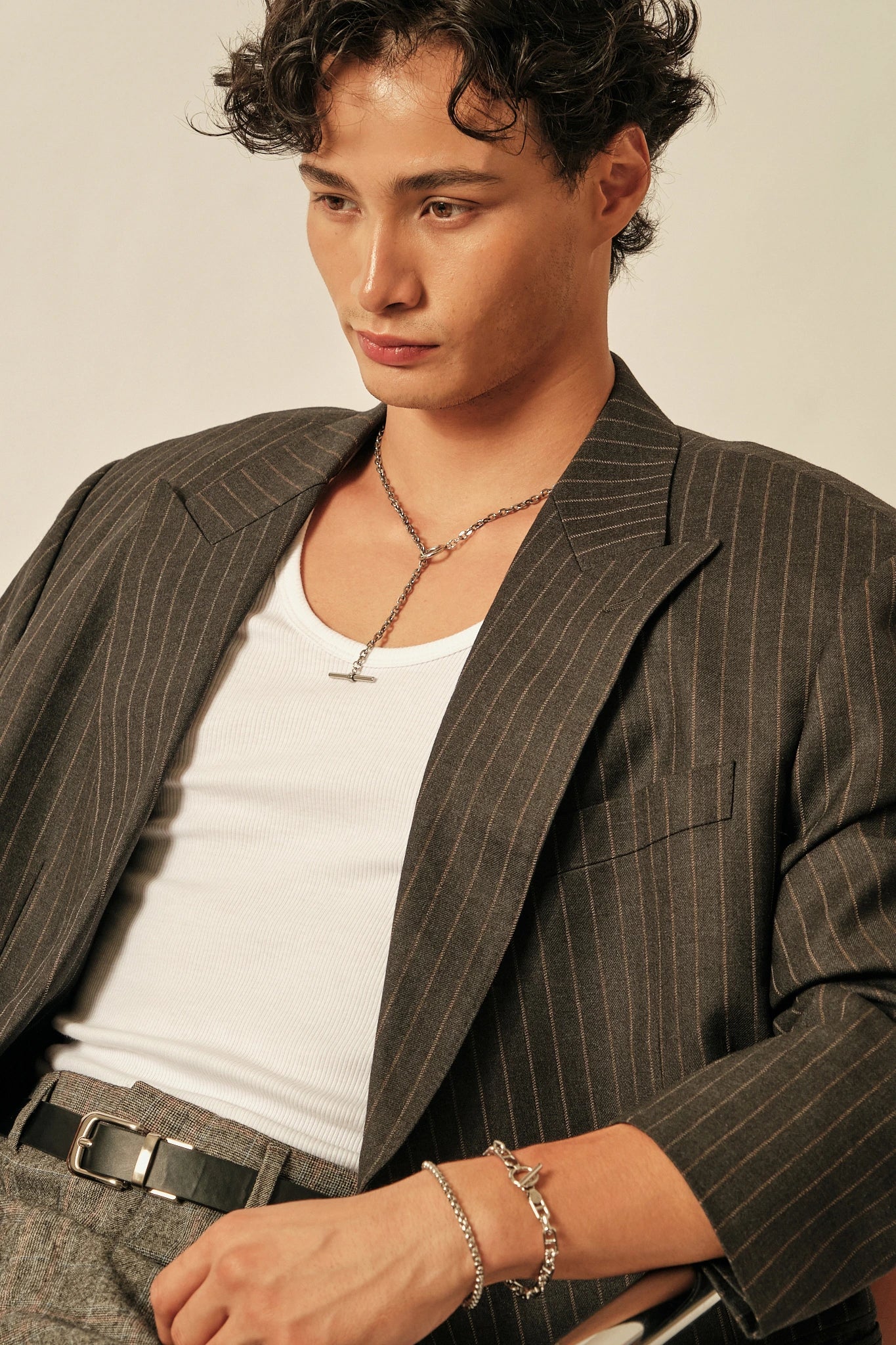 Person wearing a pinstripe blazer over a white shirt with a neutral background