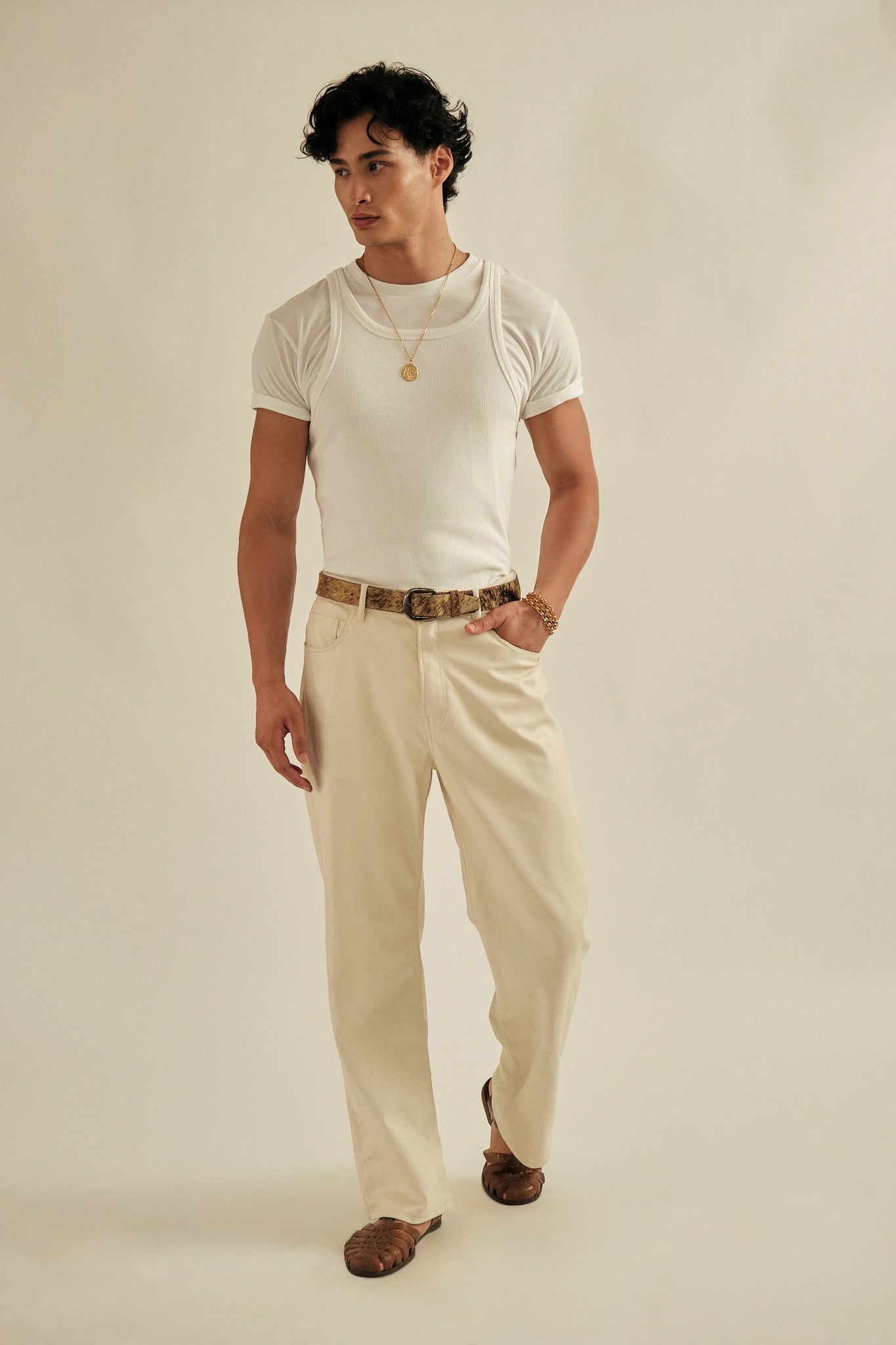 Man wearing a white t-shirt and beige pants against a plain background