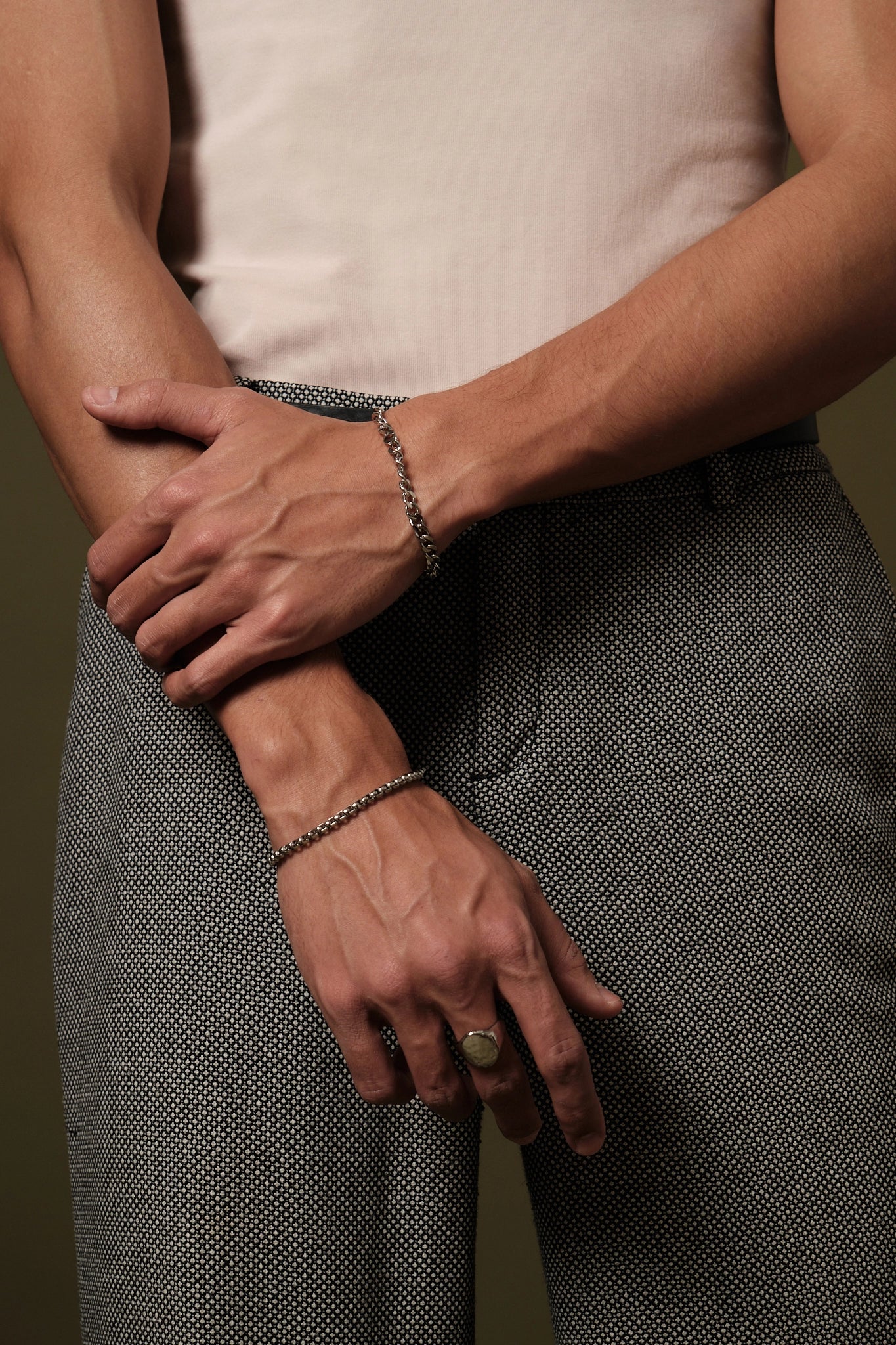 Person wearing a bracelet and ring with a neutral background
