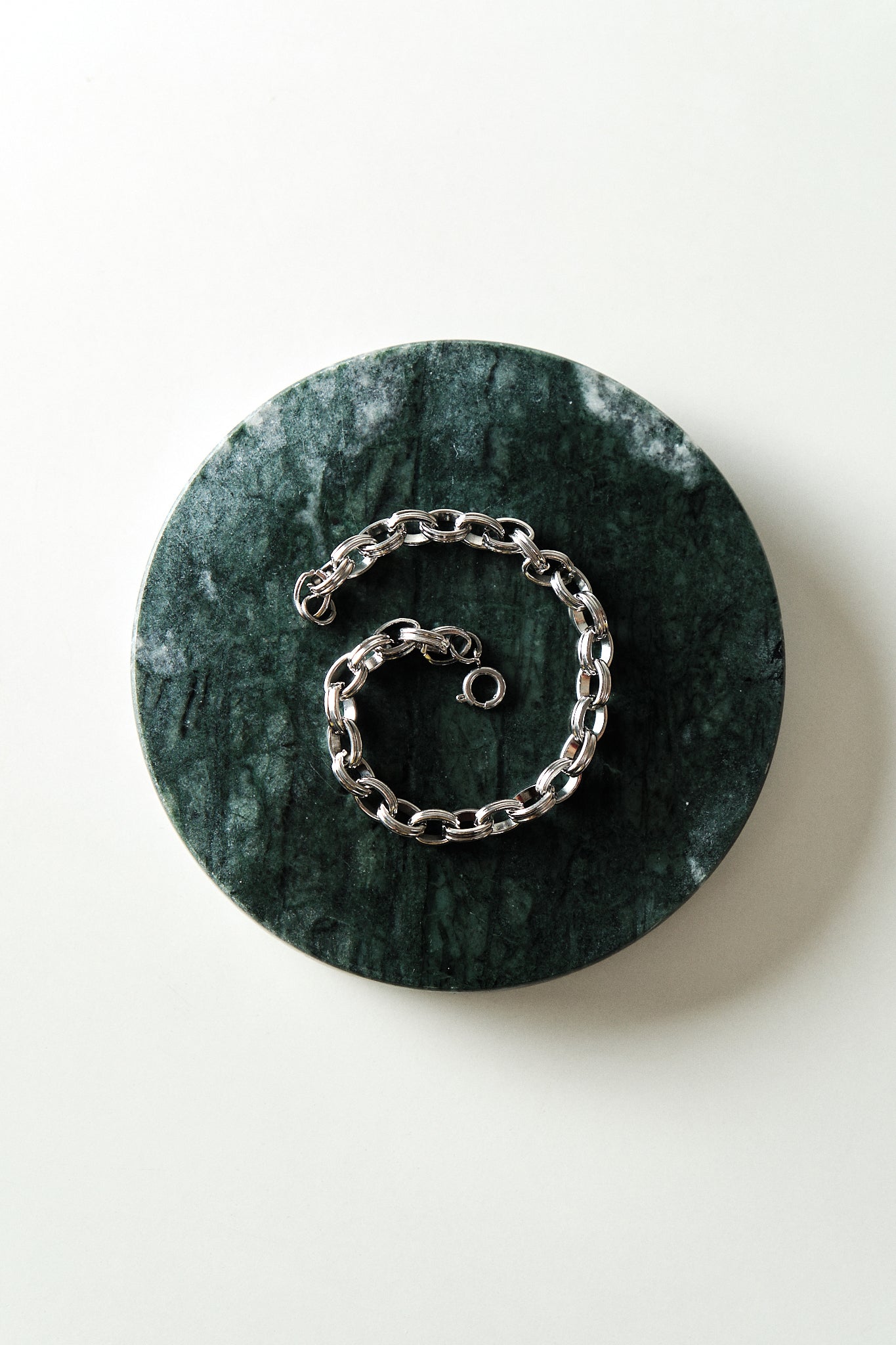 Silver chain bracelet on a green marble coaster