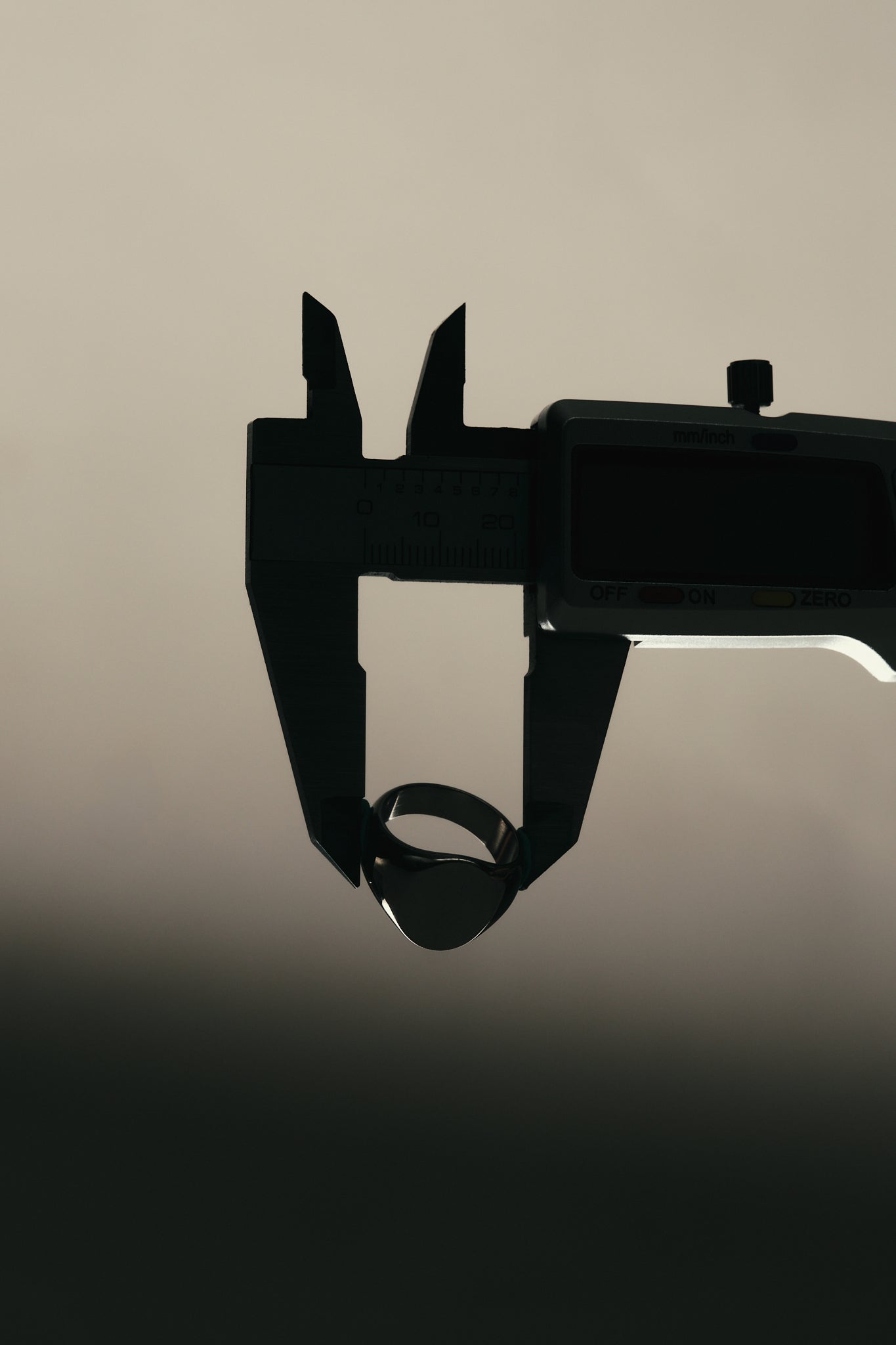 Silhouette of a digital caliper on a beige background