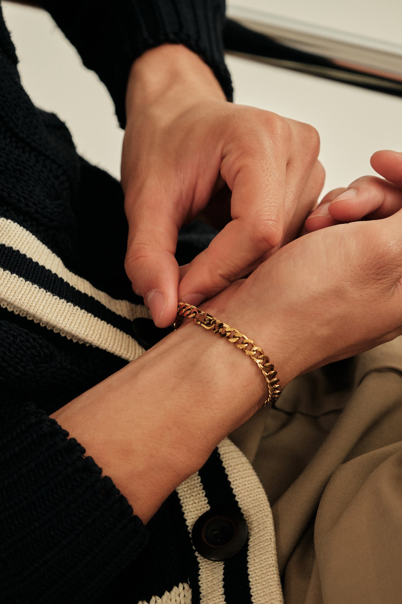 Close-up of hands wearing a gold bracelet with a blurred background