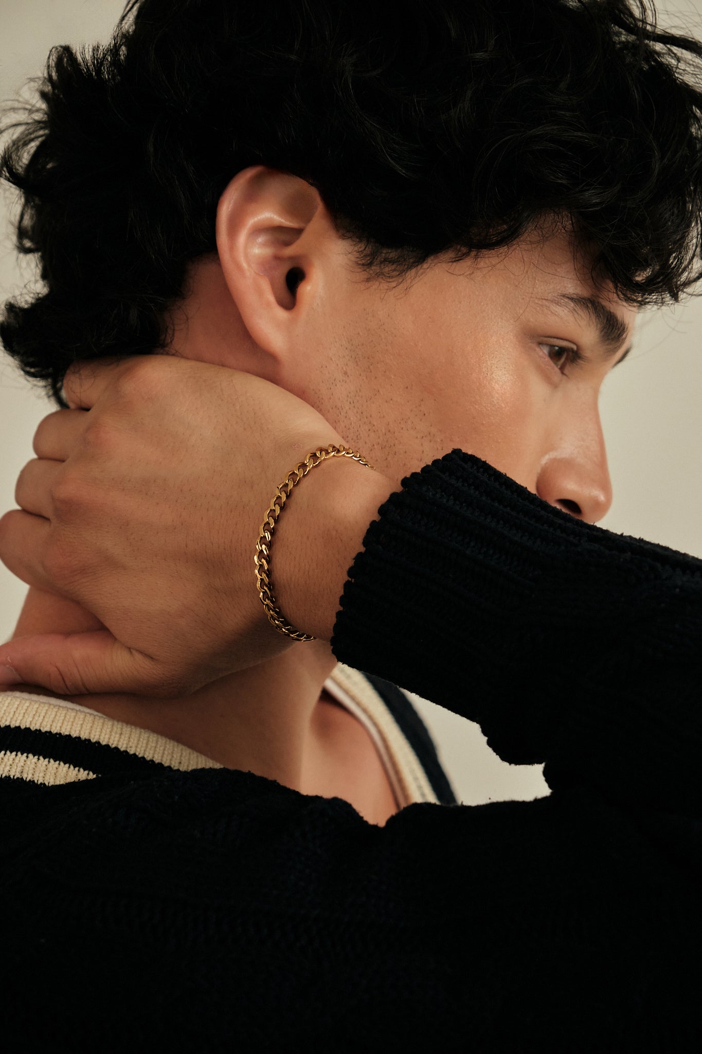 Person wearing a gold bracelet with a neutral background